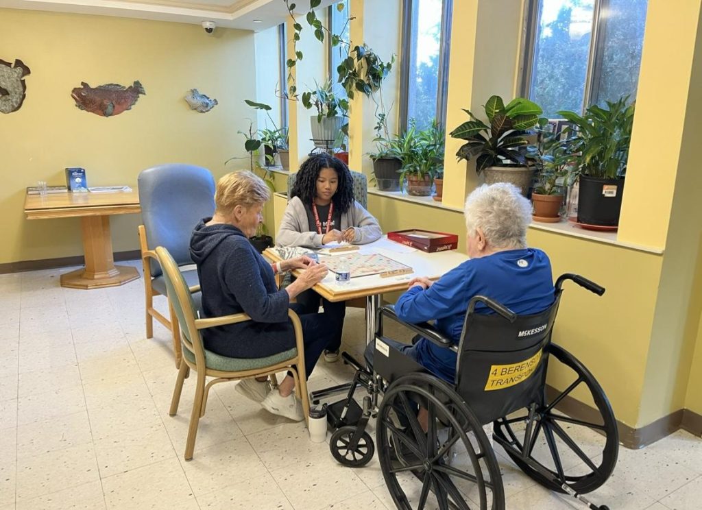 Kristina Honda with two senior adults playing Scrabble.