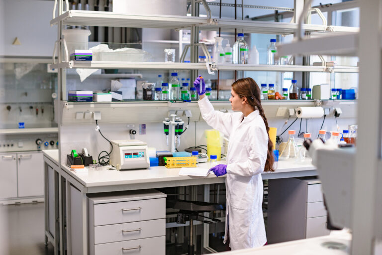 Young attractive woman scientist working in scientific chemical laboratory with her notes